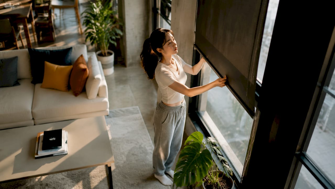 Person adjusting black roller window shades