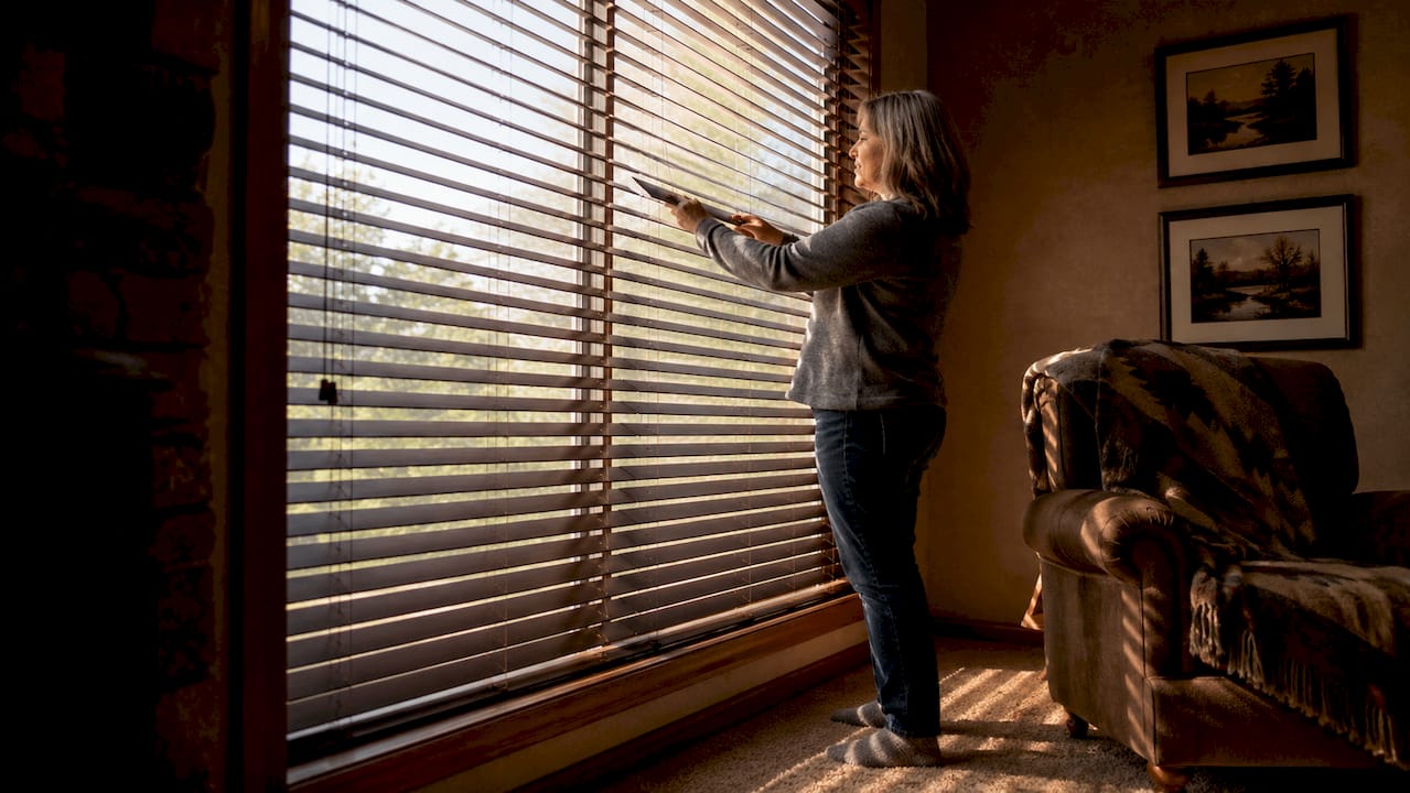 Woman installing 2 inch window blinds at home