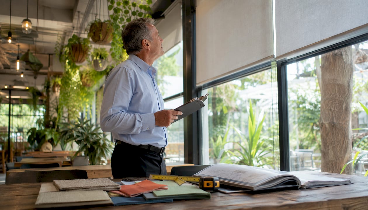 Facility manager inspecting commercial blinds at window