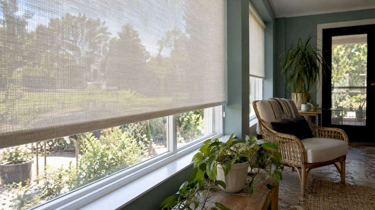 Woven roller shade in natural beige fabric with a semi-sheer texture, partially lowered; How Fabric Opacity Shapes daylight softly.