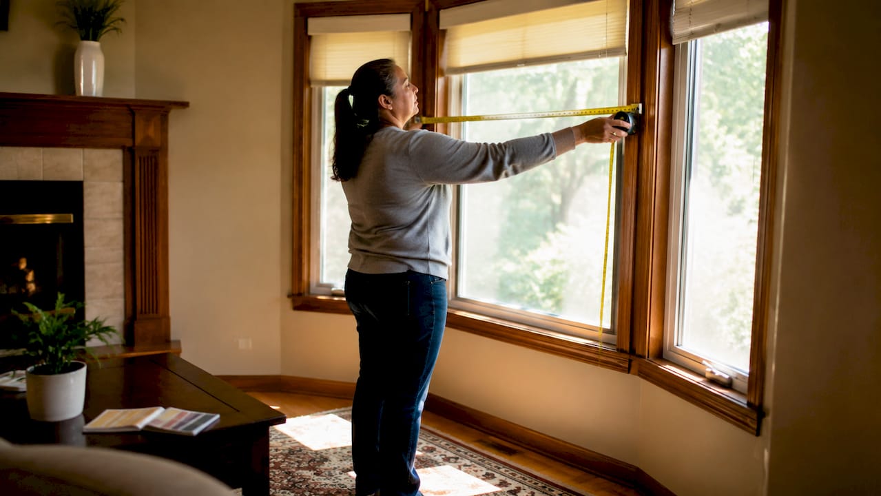 Woman measuring window width for vertical blinds